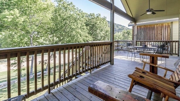 A wooden deck with a railing, outdoor seating, and a view of trees and hills. - Cowboy Lodge Rr94404 #4 4 Bedroom Home by RedAwning (New Braunfels)