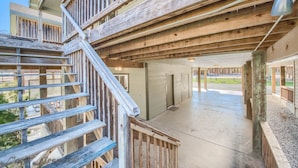 A wooden staircase leading to a covered outdoor area with a concrete floor and a view of a green landscape. - Cowboy Lodge Rr94404 #4 4 Bedroom Home by RedAwning (New Braunfels)