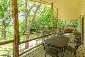 A covered outdoor deck with a table and chairs, surrounded by trees and a wooden fence. - Wagon Wheel Rr9084ww 3 Bedroom Home by RedAwning (New Braunfels)