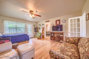 A spacious living room with a bed, a green armchair, a floral sofa, and a television. - Bluebonnet Rr9084bc 1 Bedroom Home by RedAwning (New Braunfels)