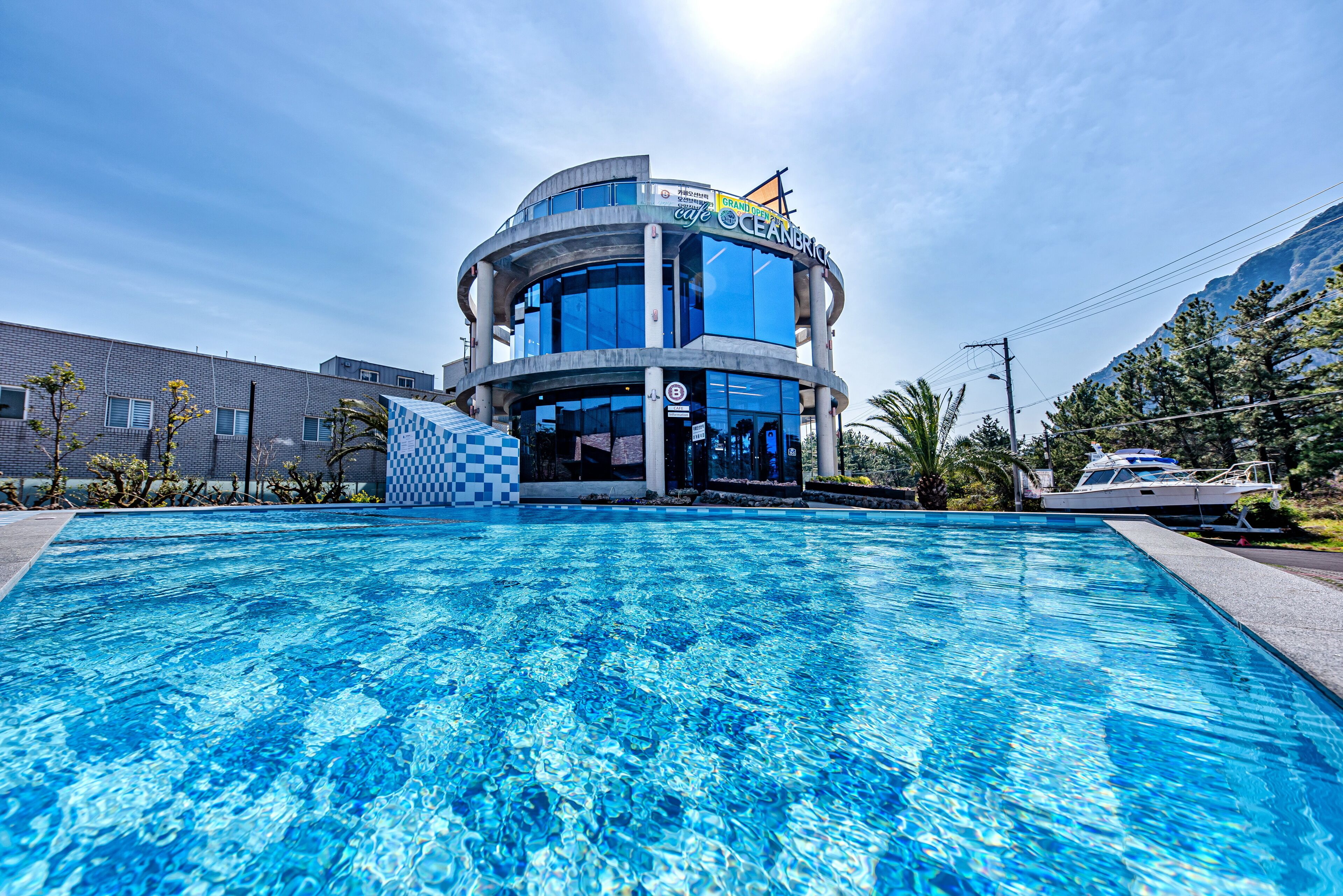 A modern building with a pool in front, featuring a checkered pattern near the entrance.