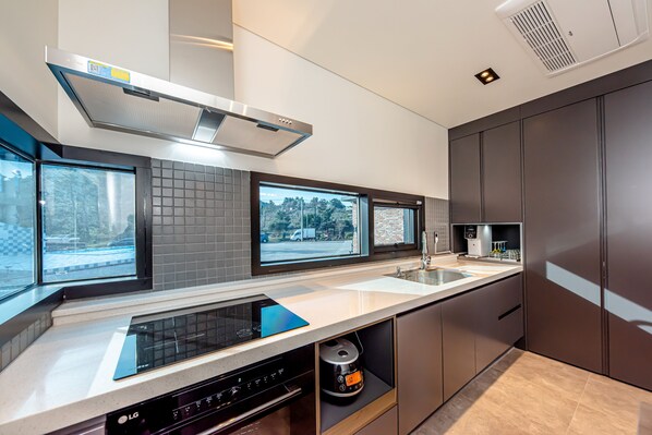 A modern kitchen with a built-in oven, a dishwasher, and a window with a view of the street.
