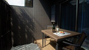 Un petit espace patio avec une table en bois, une bouteille de champagne et un saladier de fruits.