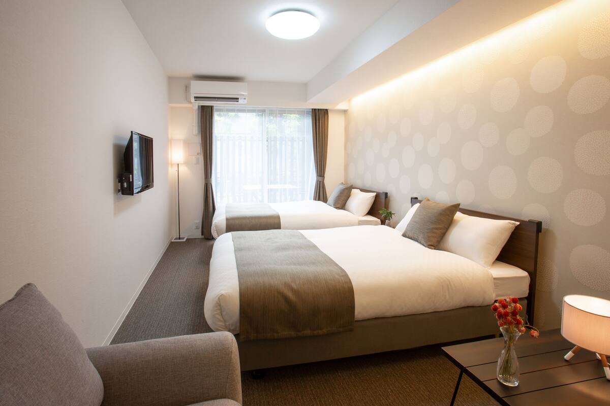 A hotel room with two beds, a TV, a desk, and a chair.