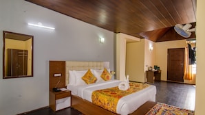 A hotel room with a wooden bed, bedside tables, a nightstand, a wall-mounted light, and a ceiling fan. - Muscatel Grand Silk Route (Gangtok)