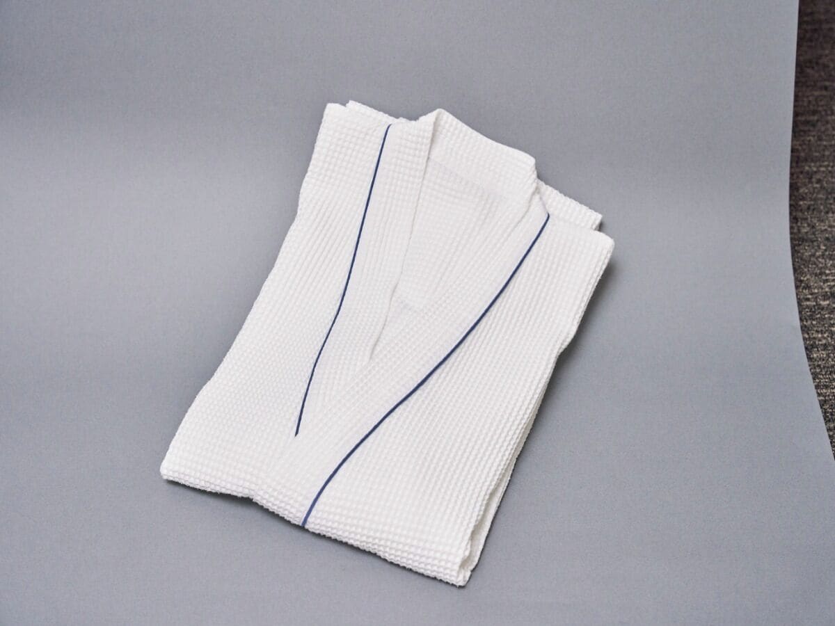 A folded white towel with blue stripes on a grey surface.