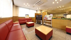 A restaurant with red seating, a television, and a menu stand.