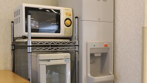 A compact kitchenette with a microwave, refrigerator, and a water dispenser.