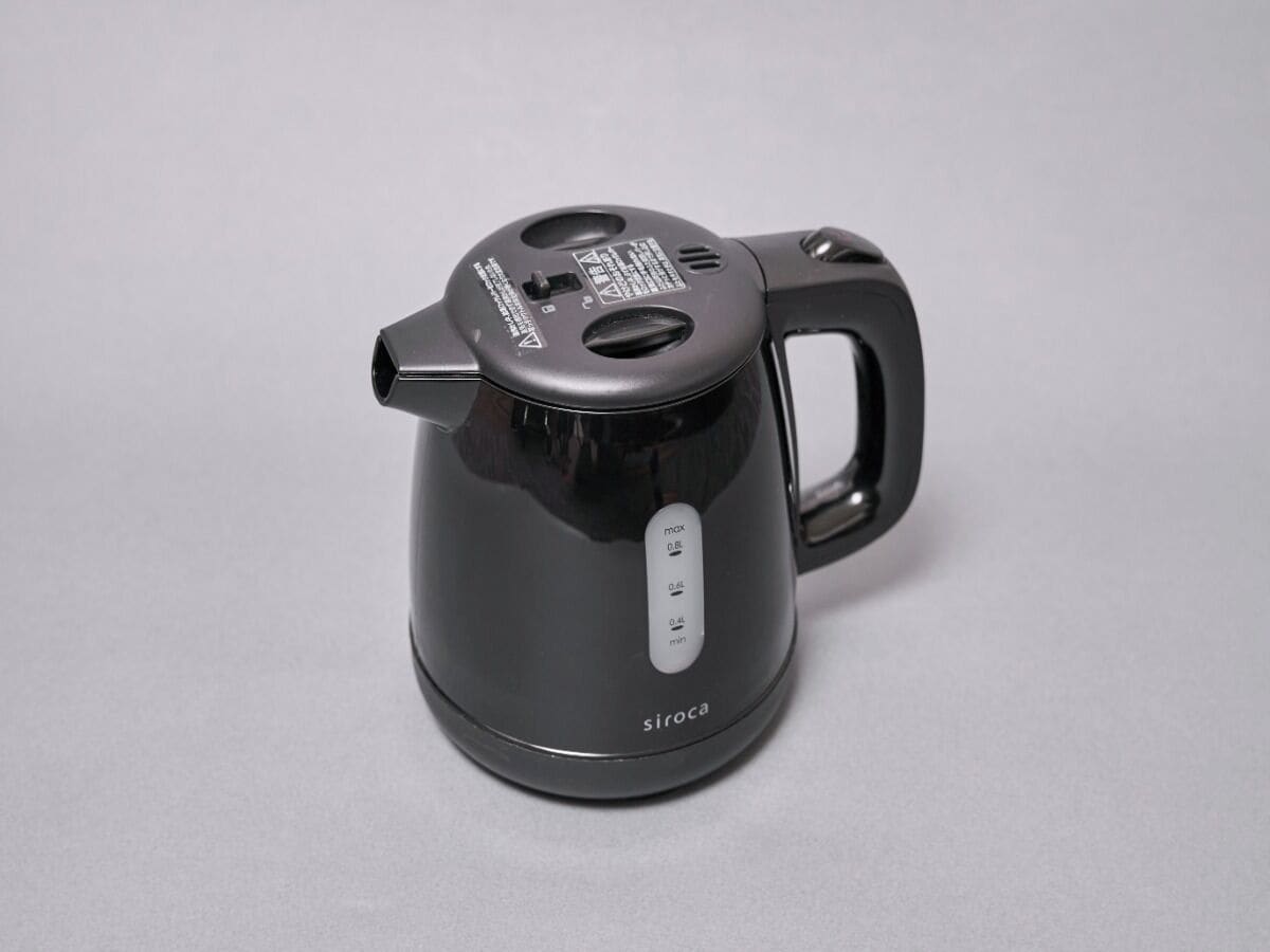 A black electric kettle with a handle and a control panel with buttons.