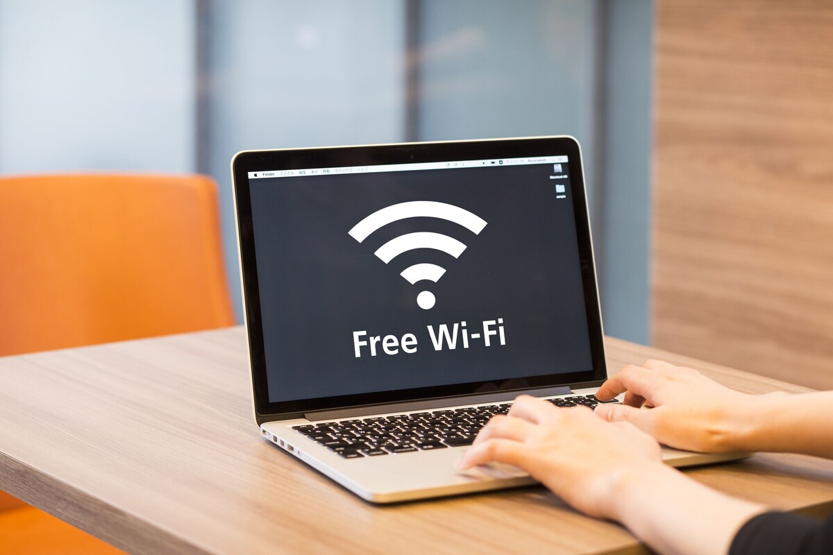 A laptop on a wooden table displaying a Wi-Fi symbol with the text "Free Wi-Fi".