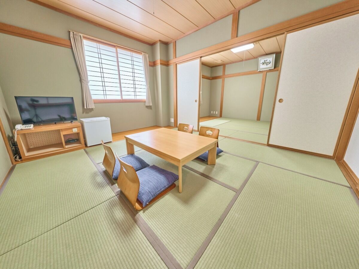 A traditional Japanese-style room with tatami flooring, a low wooden table, and a television.