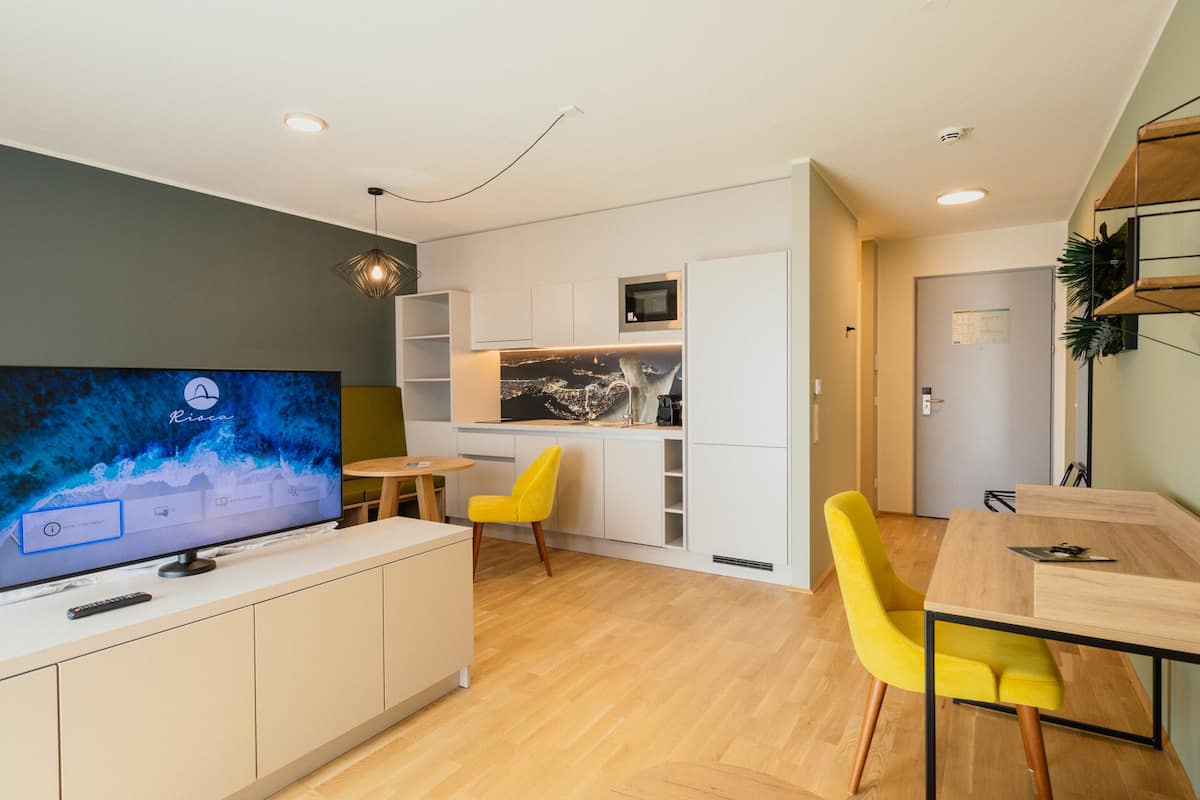 Una cocina moderna con televisor de pantalla plana, armarios de madera y una silla amarilla.