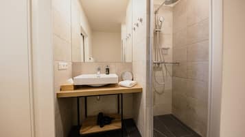 A modern bathroom with a sink, mirror, and shower.