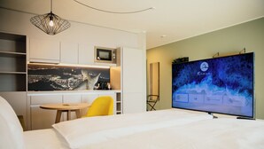 A hotel room with a bed, a desk with a chair, a flat-screen TV, and a cityscape view on the wall. - Rioca Vienna Posto 1 (Vienna)