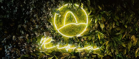 A neon sign with a heart and the word "Love" surrounded by lush greenery.