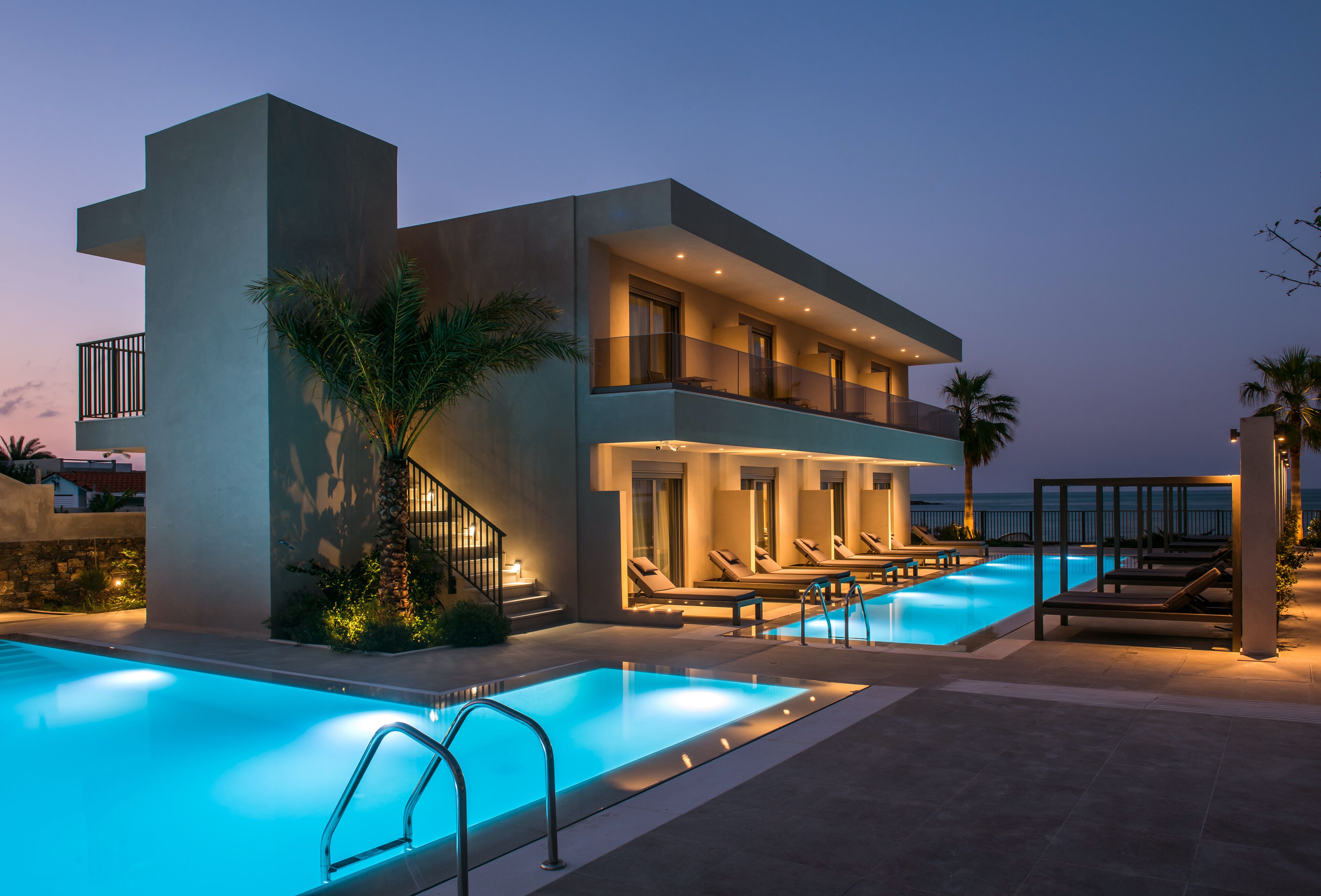 Un hotel modern amb piscina, gandules i vistes al mar.