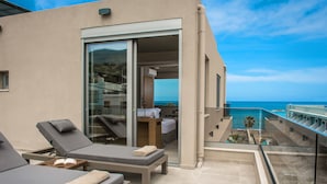 Ein Balkon mit zwei Liegestühlen, einem kleinen Tisch mit einem Buch und Blick aufs Meer.