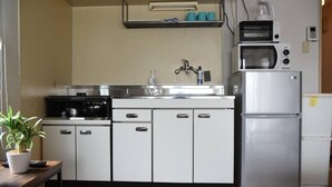 Een kleine keuken met witte kastjes, een roestvrijstalen koelkast en een magnetron.