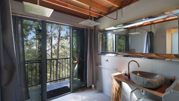 Un baño moderno con lavamanos de piedra, ventanas amplias y techo de madera.