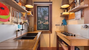 Cocina compacta con encimeras de madera, un lavamanos doble y un ventanal con vistas a árboles.