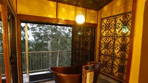 Una habitación con un ventanal grande, una bañera y una verja de hierro decorativa.