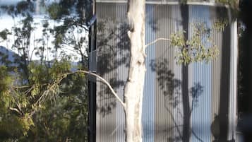 A corrugated metal building with a tree in front.