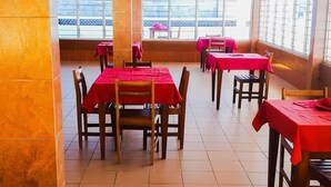 A restaurant with multiple tables and chairs, large windows, and a tiled floor. - Academia Hotel (Lomé)
