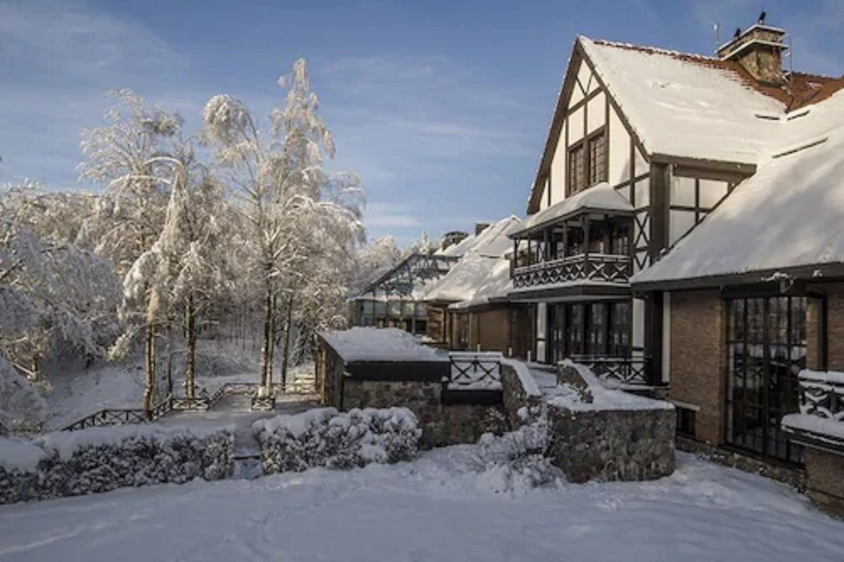 Un edificio cubierto de nieve con un estilo arquitectónico tradicional, que presenta un balcón destacado y ventanas amplias.
