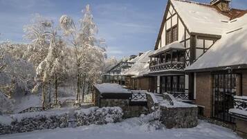 Un edificio cubierto de nieve con un estilo arquitectónico tradicional, que presenta un balcón destacado y ventanas amplias.