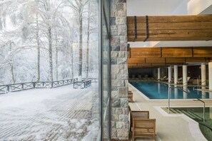Zona de piscina con vista a un bosque nevado.
