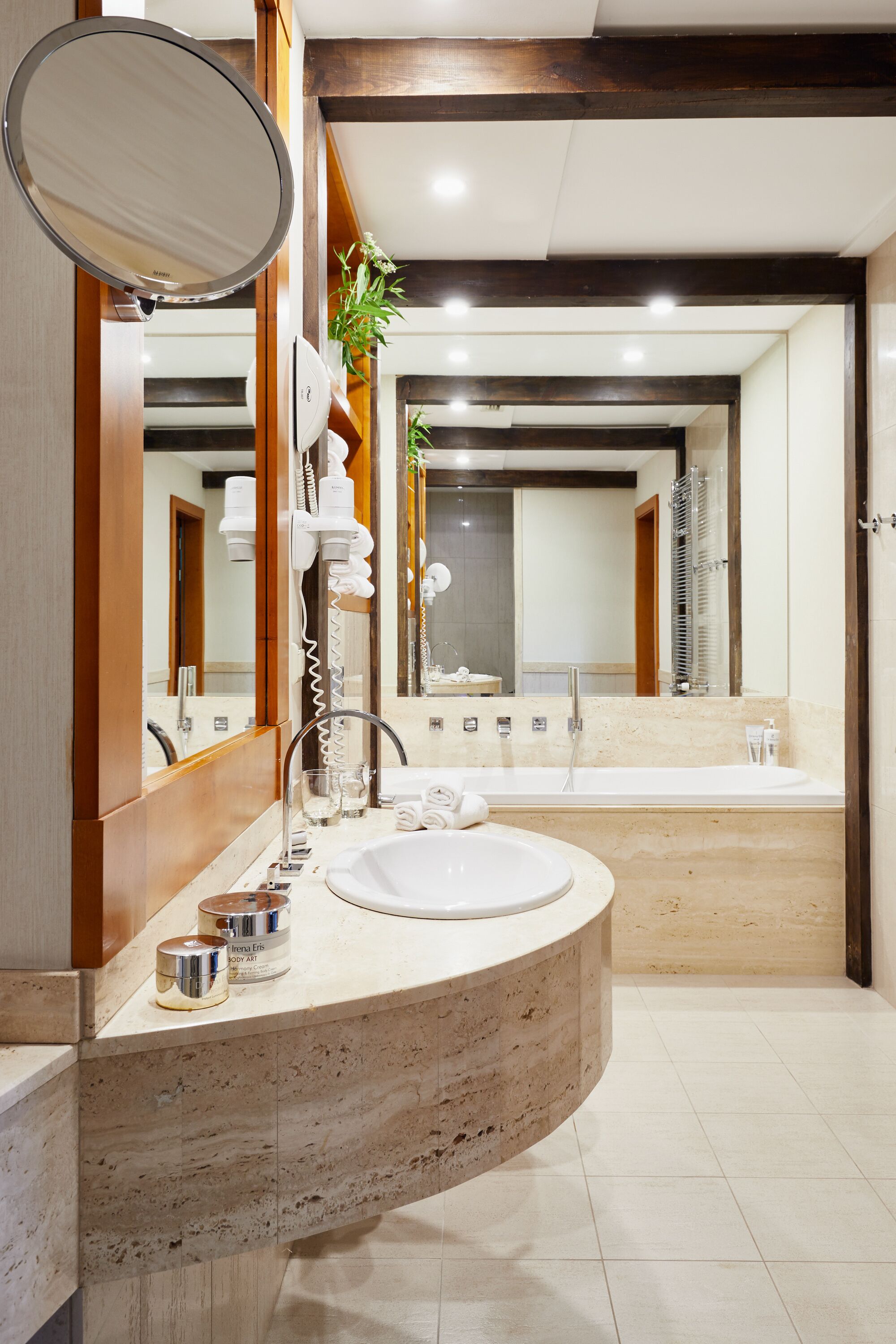 A modern bathroom with a curved marble sink, a large mirror, and a built-in shower.
