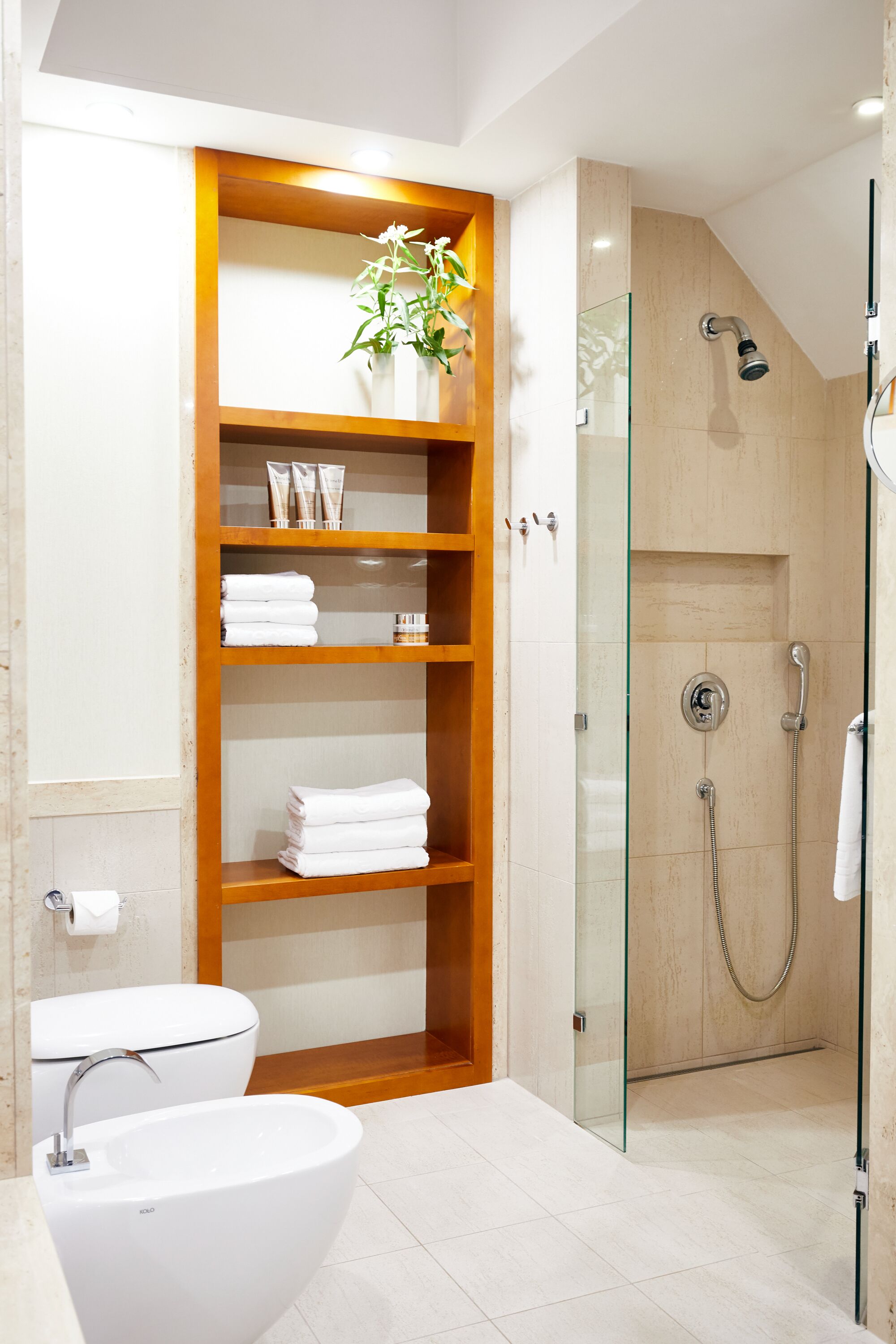 A modern bathroom with a glass-enclosed shower, a wooden vanity with shelves, and a white sink.