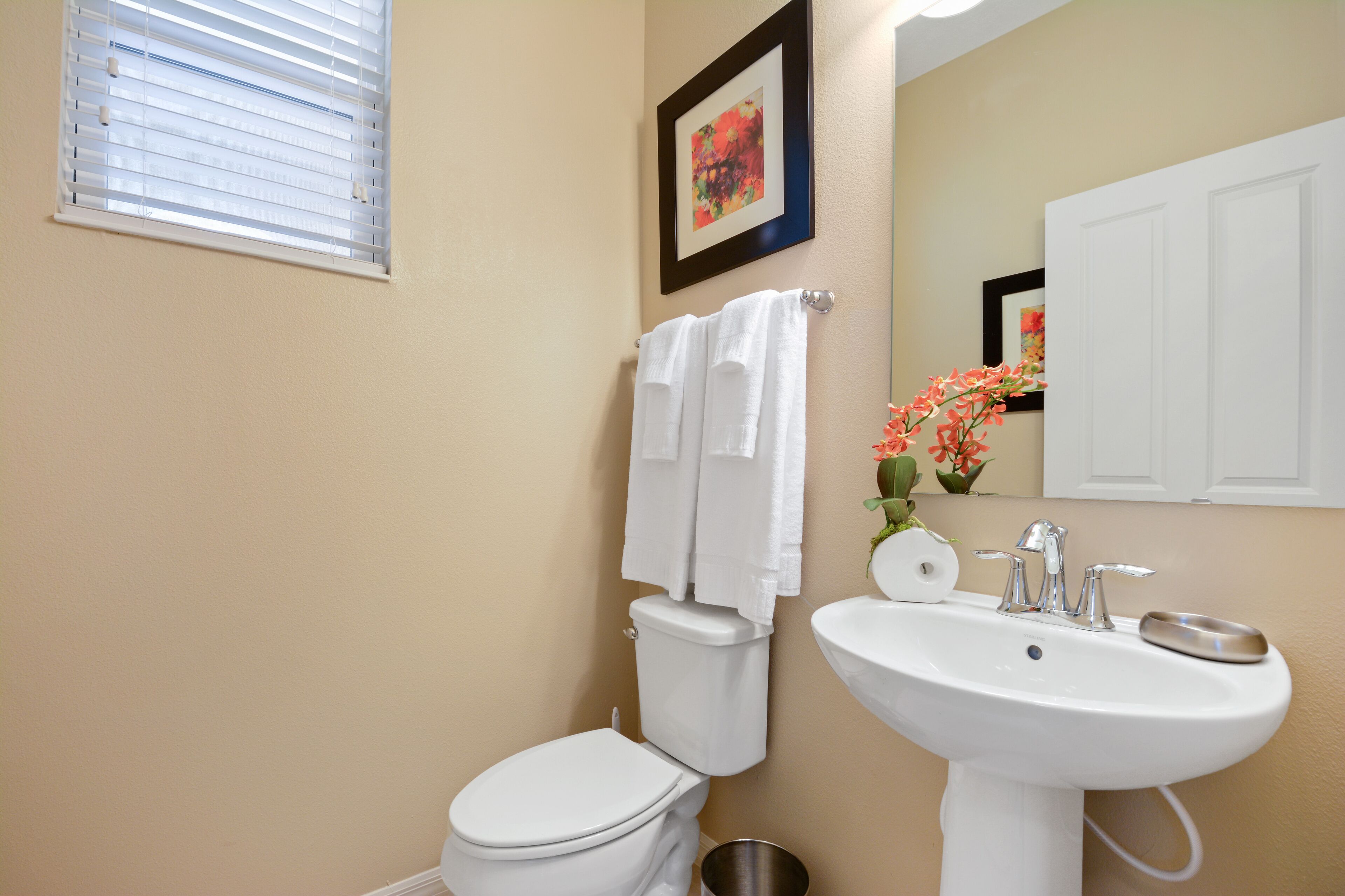 A bathroom with a toilet, sink, and a framed picture on the wall.