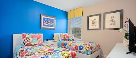 A bedroom with two beds, a desk, and a TV.