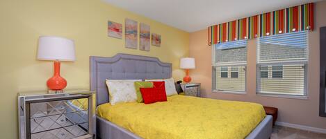 A bedroom with a bed, two nightstands, a mirror, and a window with blinds.