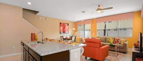 Una cocina moderna con encimeras de granito, una isla integrada y un comedor con sofá y sillones.