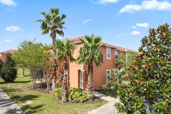 A building with a red-tiled roof, surrounded by palm trees and greenery. - Amazing Three Bedrooms w Spa/Jacuzzi close Disney @ Encantada 3012 (Kissimmee)