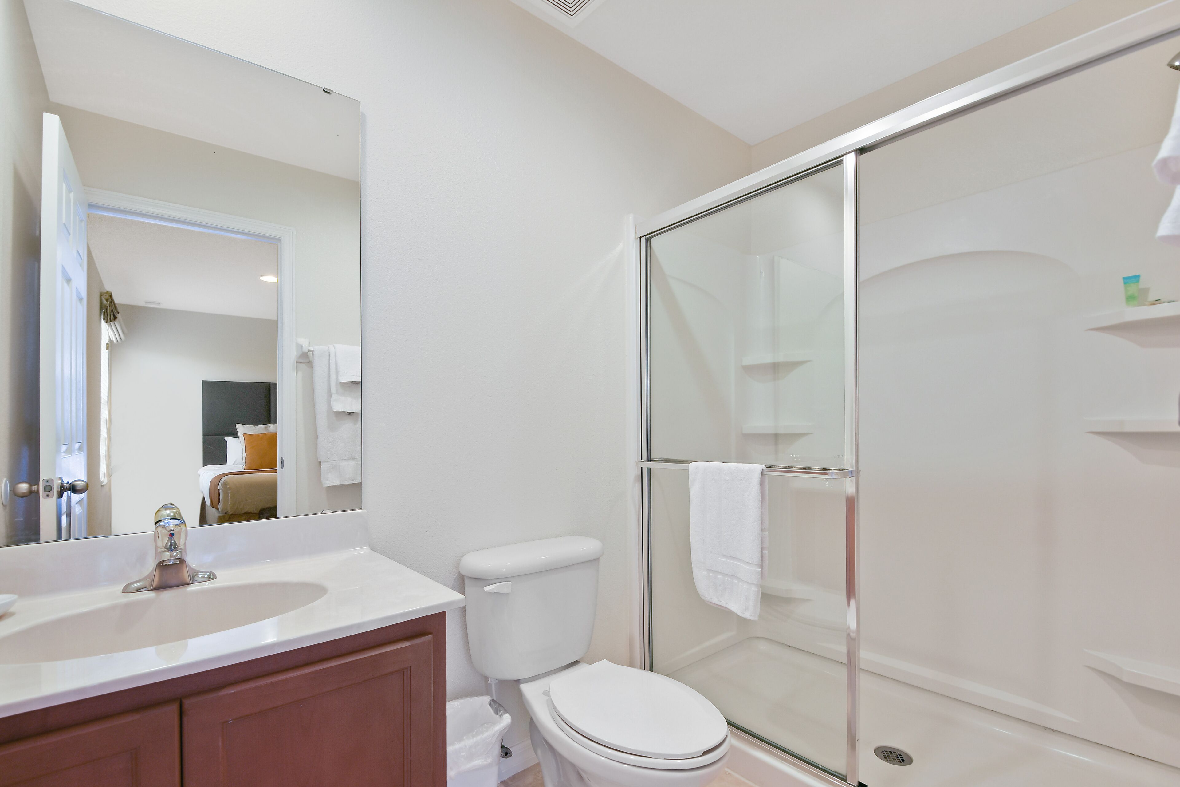 A bathroom with a white sink, toilet, and glass-enclosed shower.