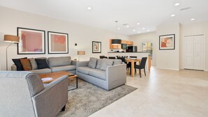 Una sala moderna con un sofá gris, una mesa de centro y un comedor con una mesa y sillas de madera.