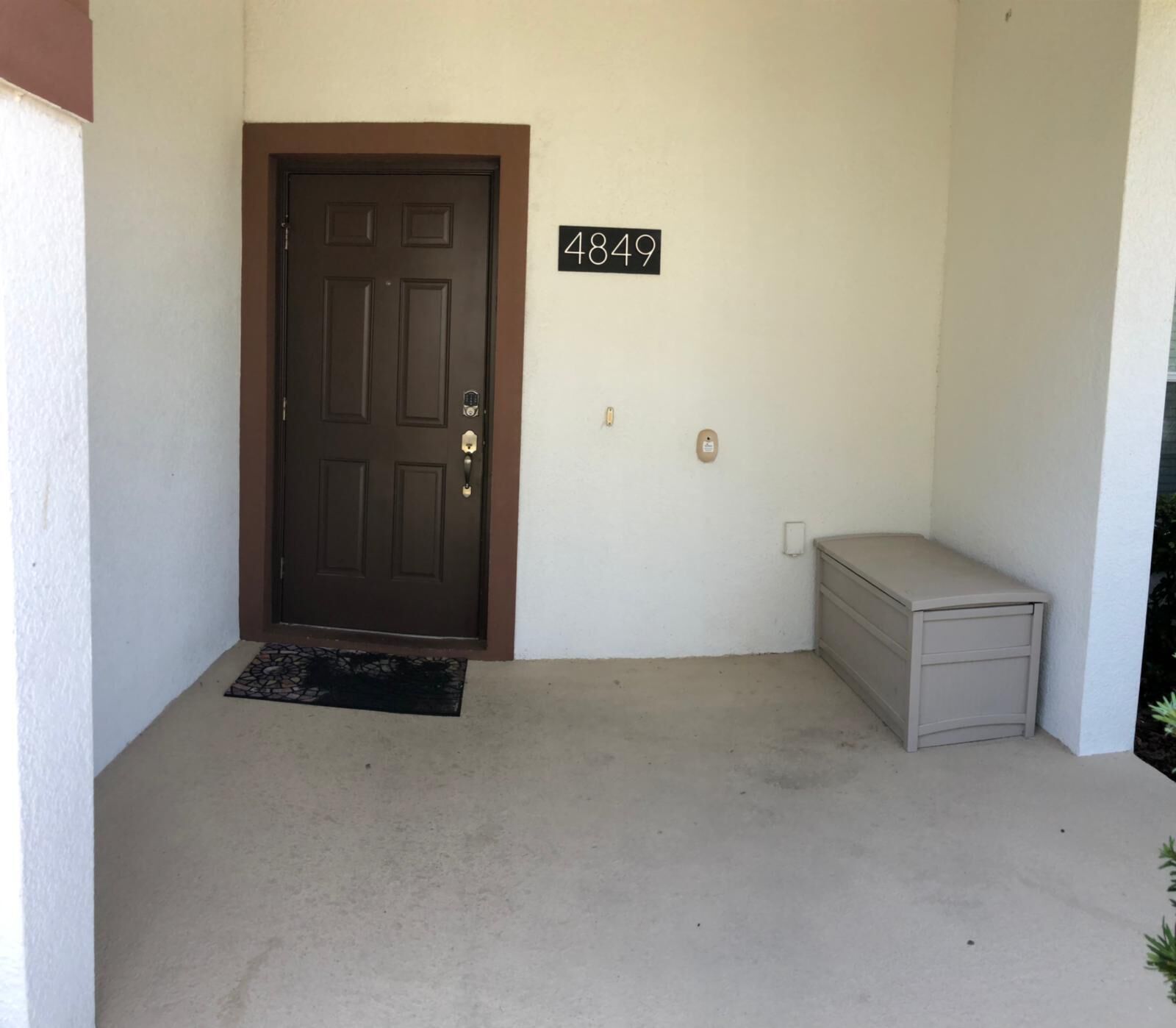 A front door with a number plate '4849', a small bench, and a doormat.