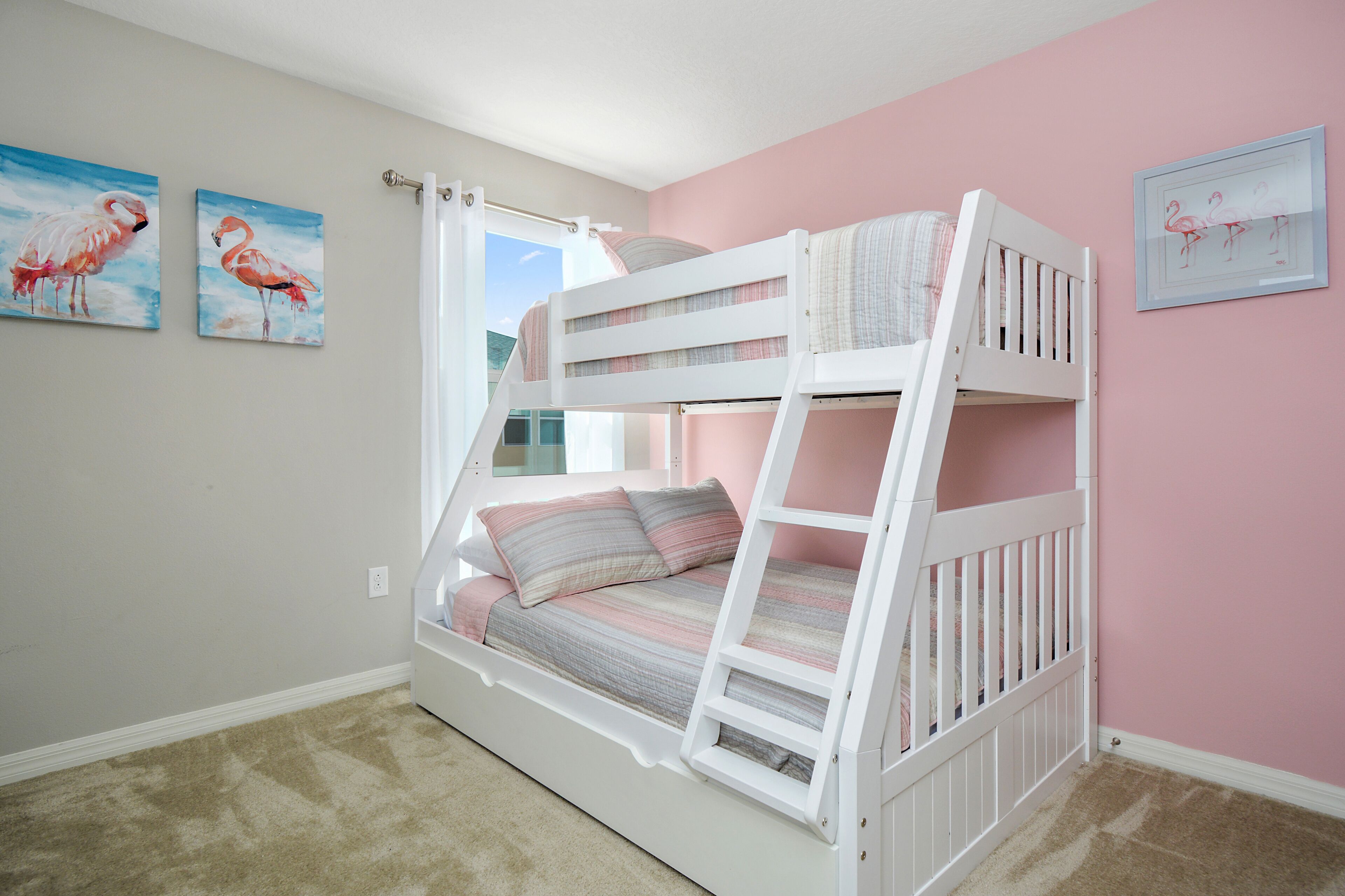 A bunk bed room with a window, two wall paintings, and a carpeted floor.