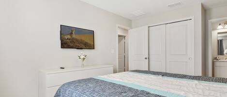 A bedroom with a bed, a dresser, a painting of a cheetah, and a closet.