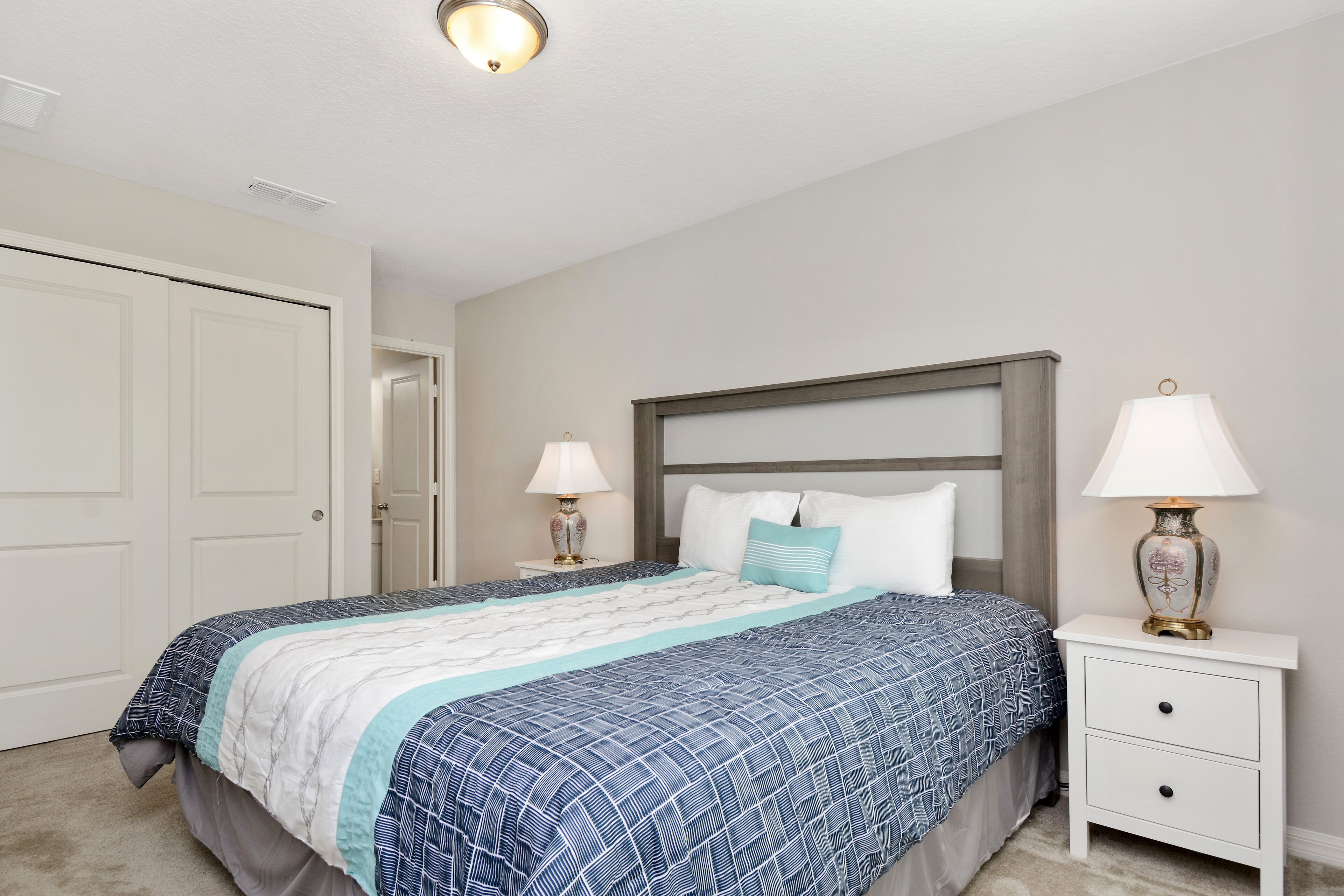 Une chambre à coucher avec un lit, des tables de chevet et une porte.