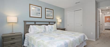 Un dormitorio con cama, mesitas de noche y una puerta que da a otra habitación.
