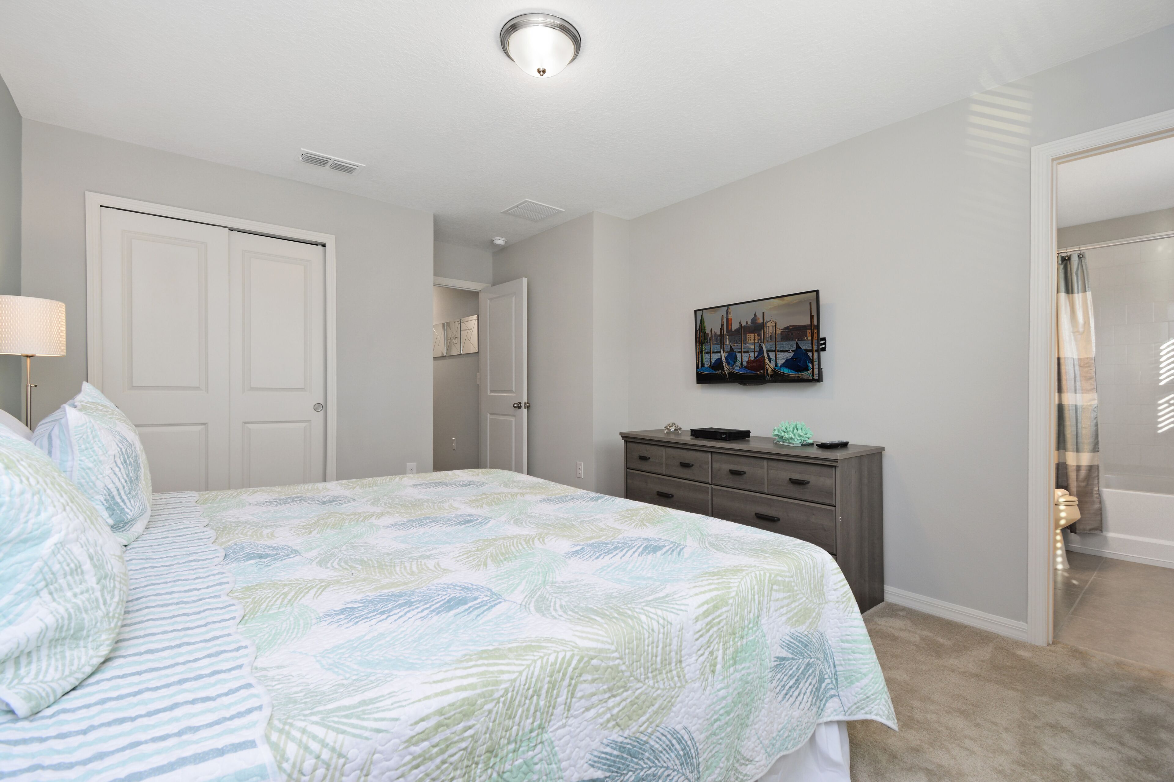 A bedroom with a bed, dresser, and a painting on the wall.