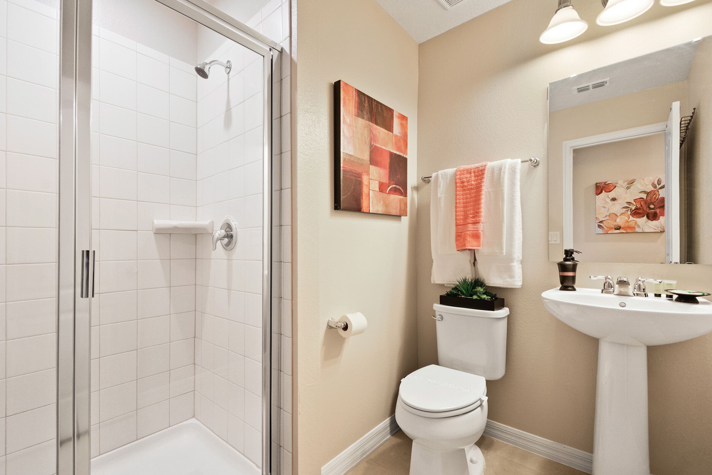 Une salle de bain avec une douche à parois de verre, des toilettes, un lavabo et deux porte-serviettes fixés au mur.