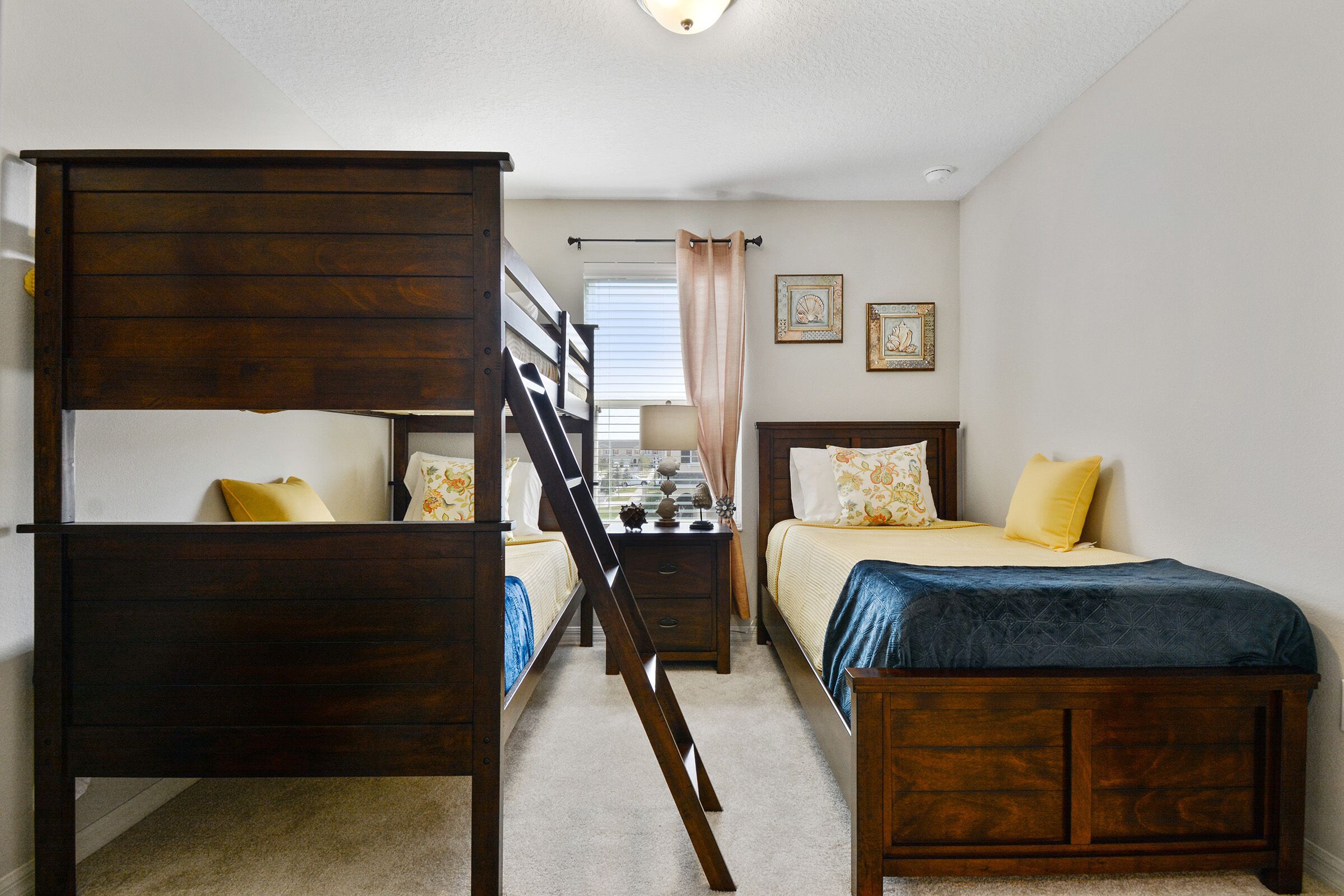 A bedroom with a bunk bed, a single bed, a dresser, and a staircase.