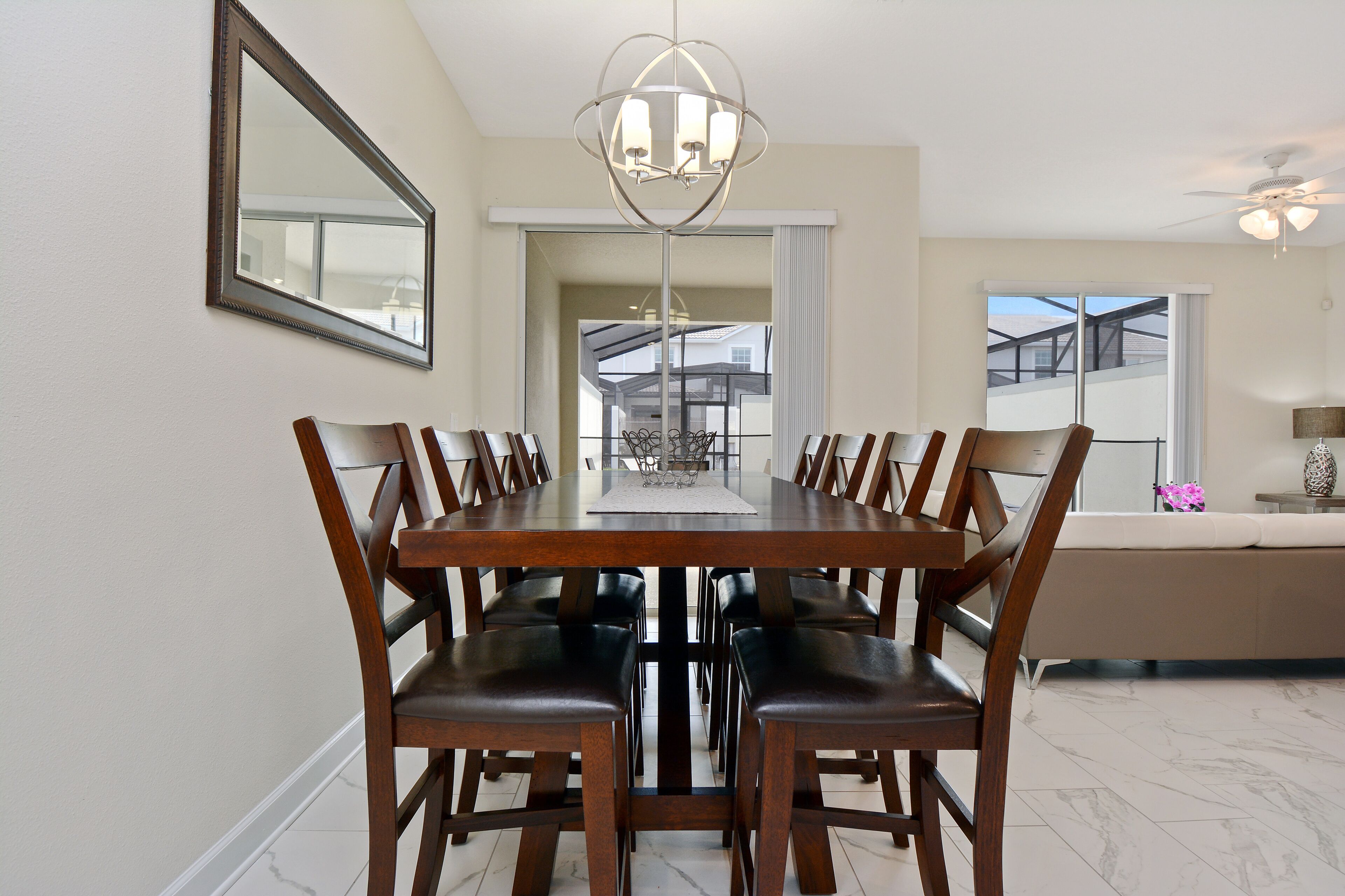 A dining area with a wooden table and chairs, a chandelier, and a view of the outside.