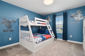 A bunk bed room with blue walls, a window with curtains, and a ceiling light.