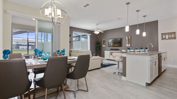 A modern kitchen with a central island, a dining area with a large table and chairs, and a living area with a sofa and TV. - Four Bedroom Close to Disney w/ Screened Pool @StoreyLake 4910 (Kissimmee)